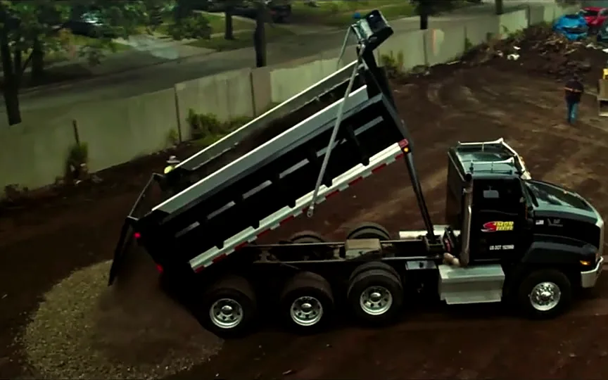 Aerial view of a dump truck spreading base stone on a lot under construction